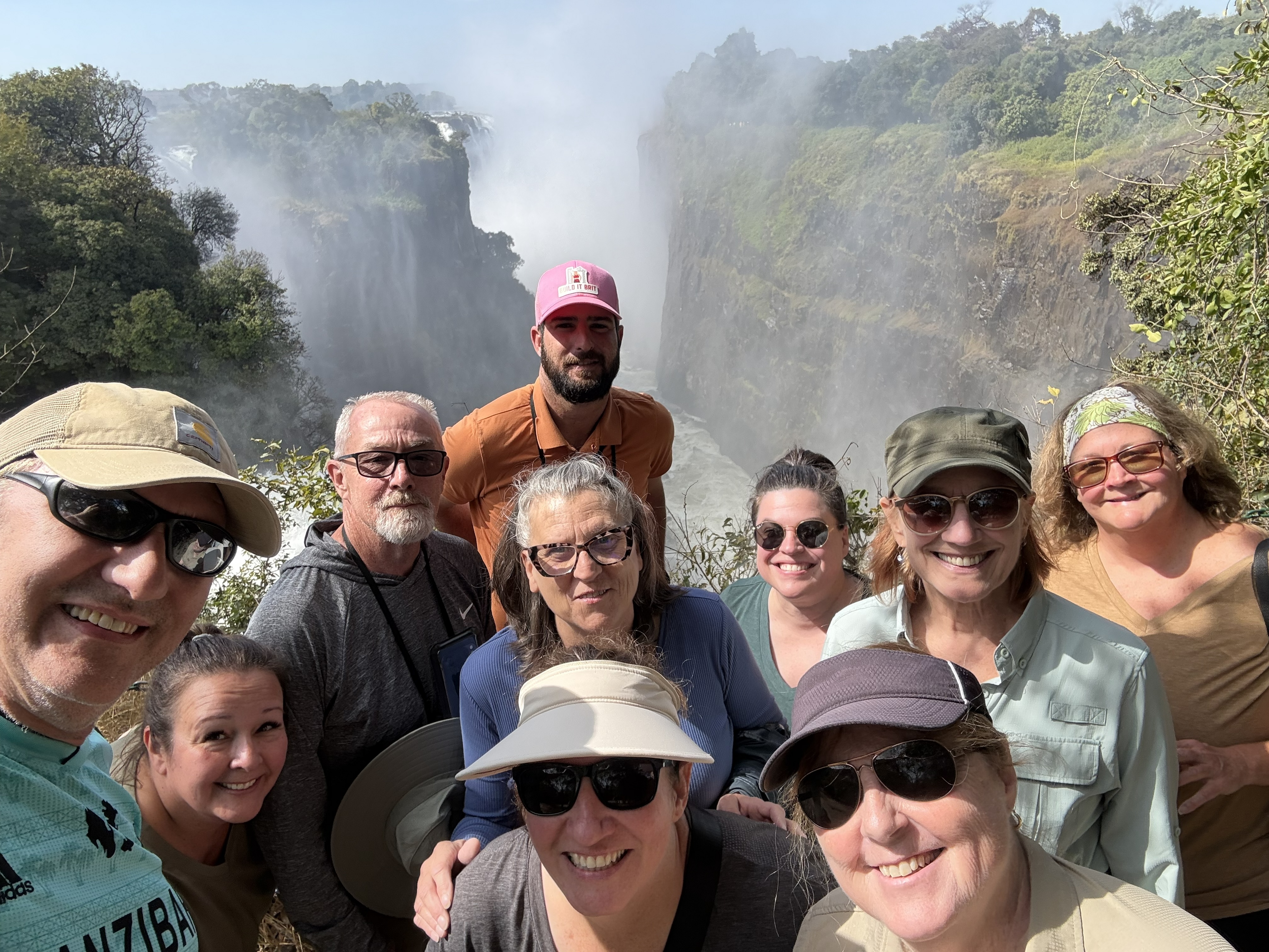 The whole group, Dylan included, assembled by way of my fully-extended selfie arm. Getting ten people and a guide into one frame at the edge of a waterfall is a skill, and I would