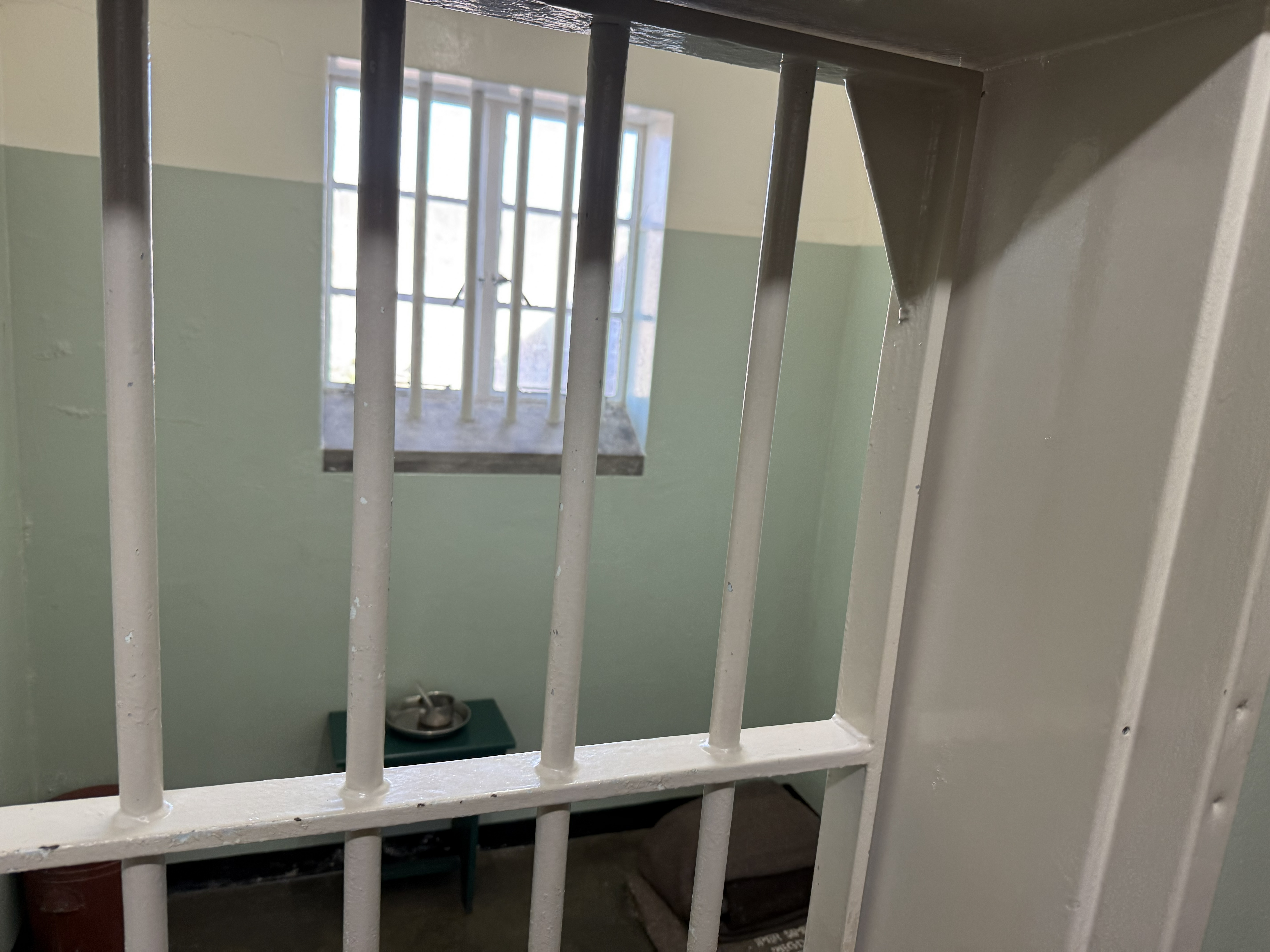 Mandela's cell — or the one immediately beside it; along this corridor the rooms were made deliberately identical, and even now you count doors and take the guide's word