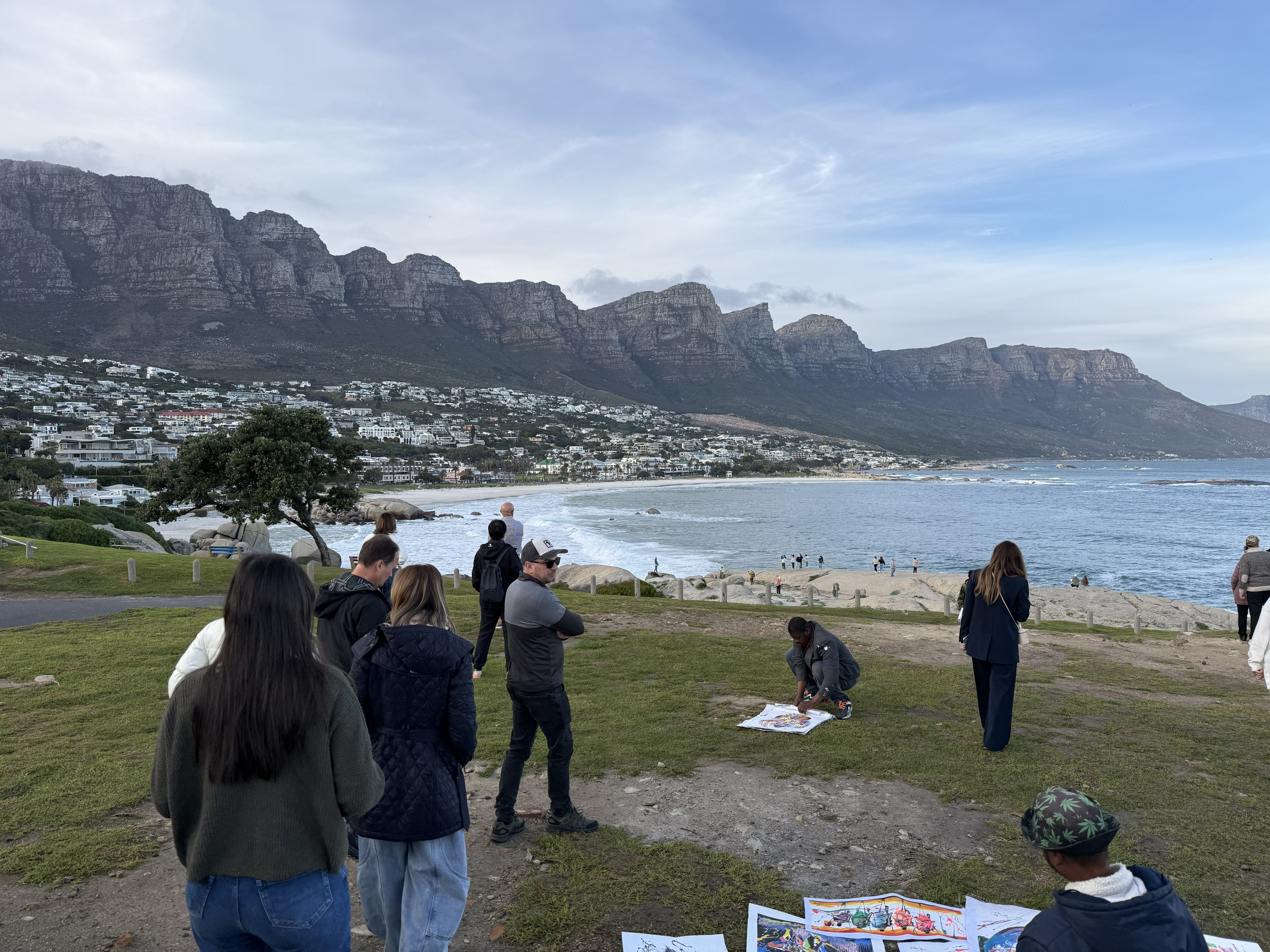 Maiden's Cove, the first stop of the day — the Twelve Apostles behind, the Atlantic in front, and a row of paintings for sale along the verge.